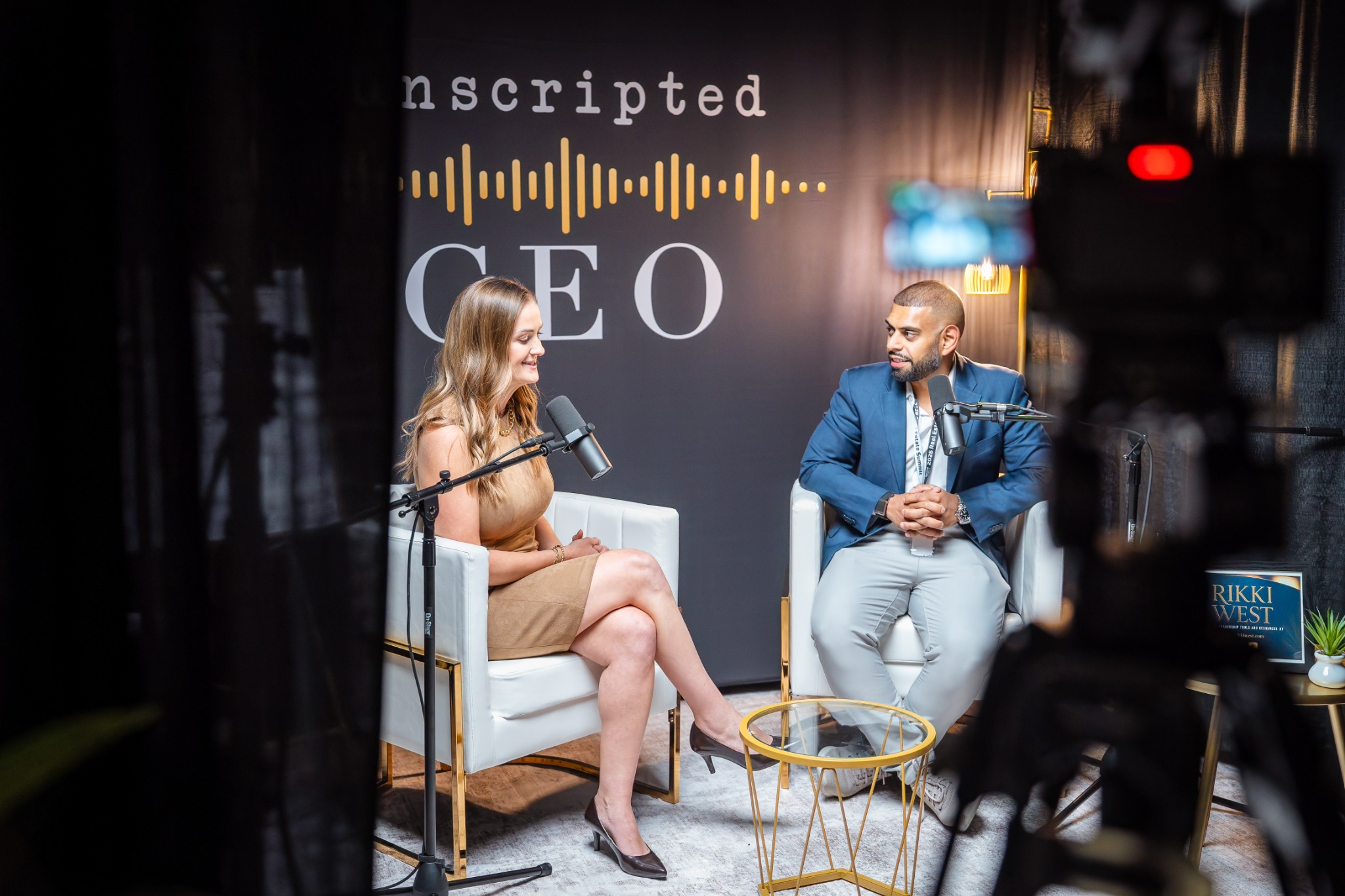 Two business leaders recording a podcast interview on a branded conference set.