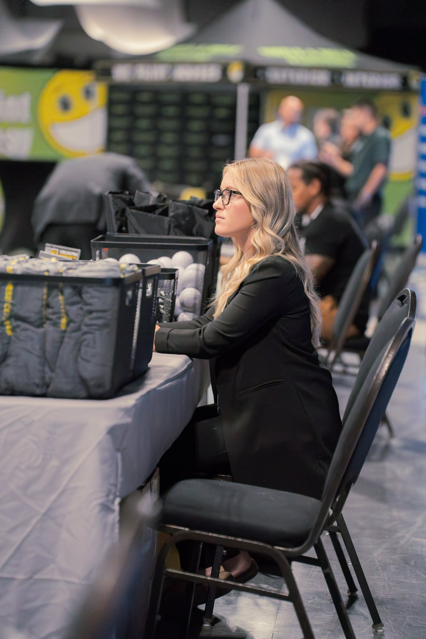 A woman working behind the scenes at a conference production table.