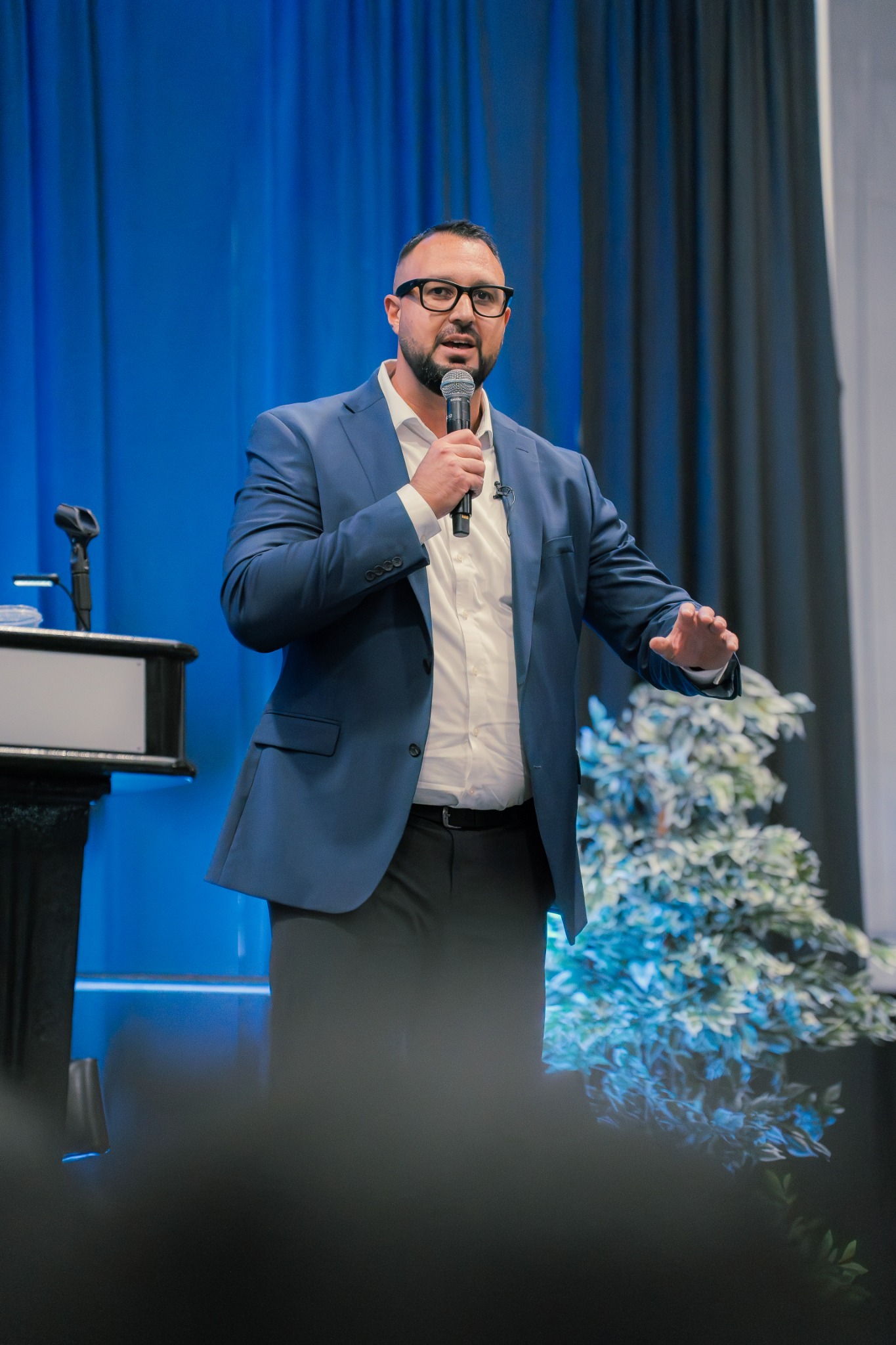 A business leader speaking into a microphone on stage.