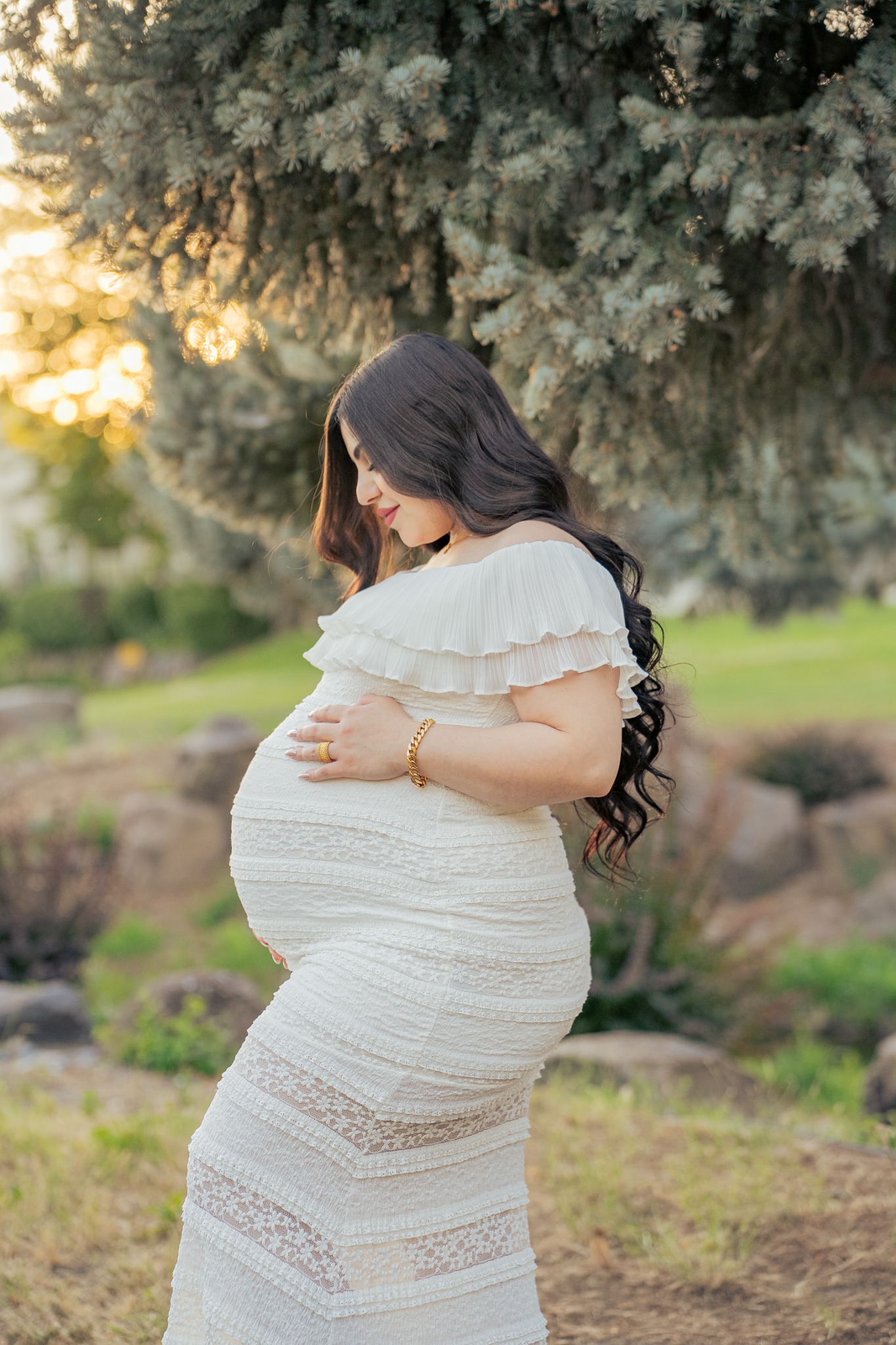 An expecting mother cradling her baby bump in soft golden light.