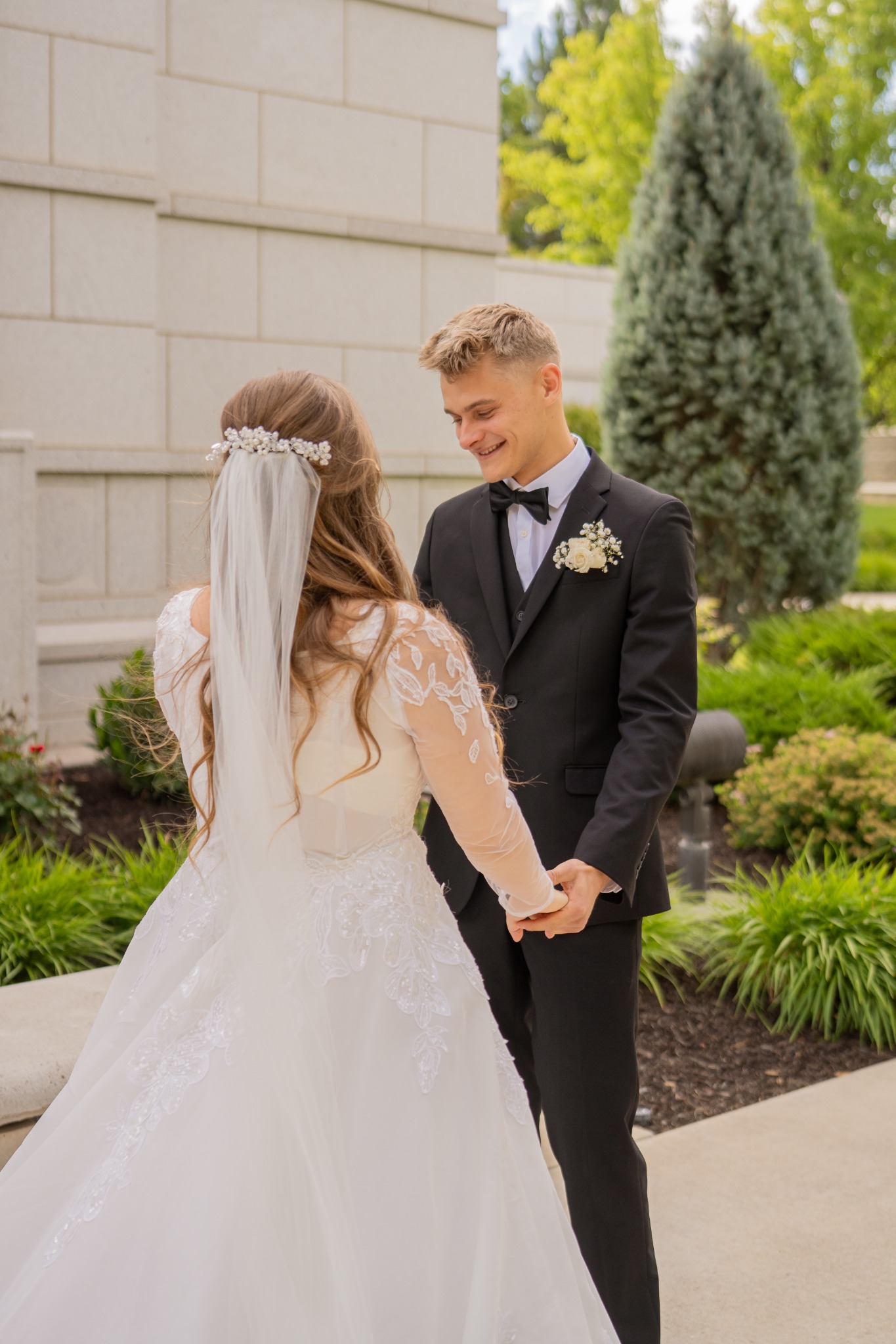 A bride and groom holding hands during their first look outside the venue.