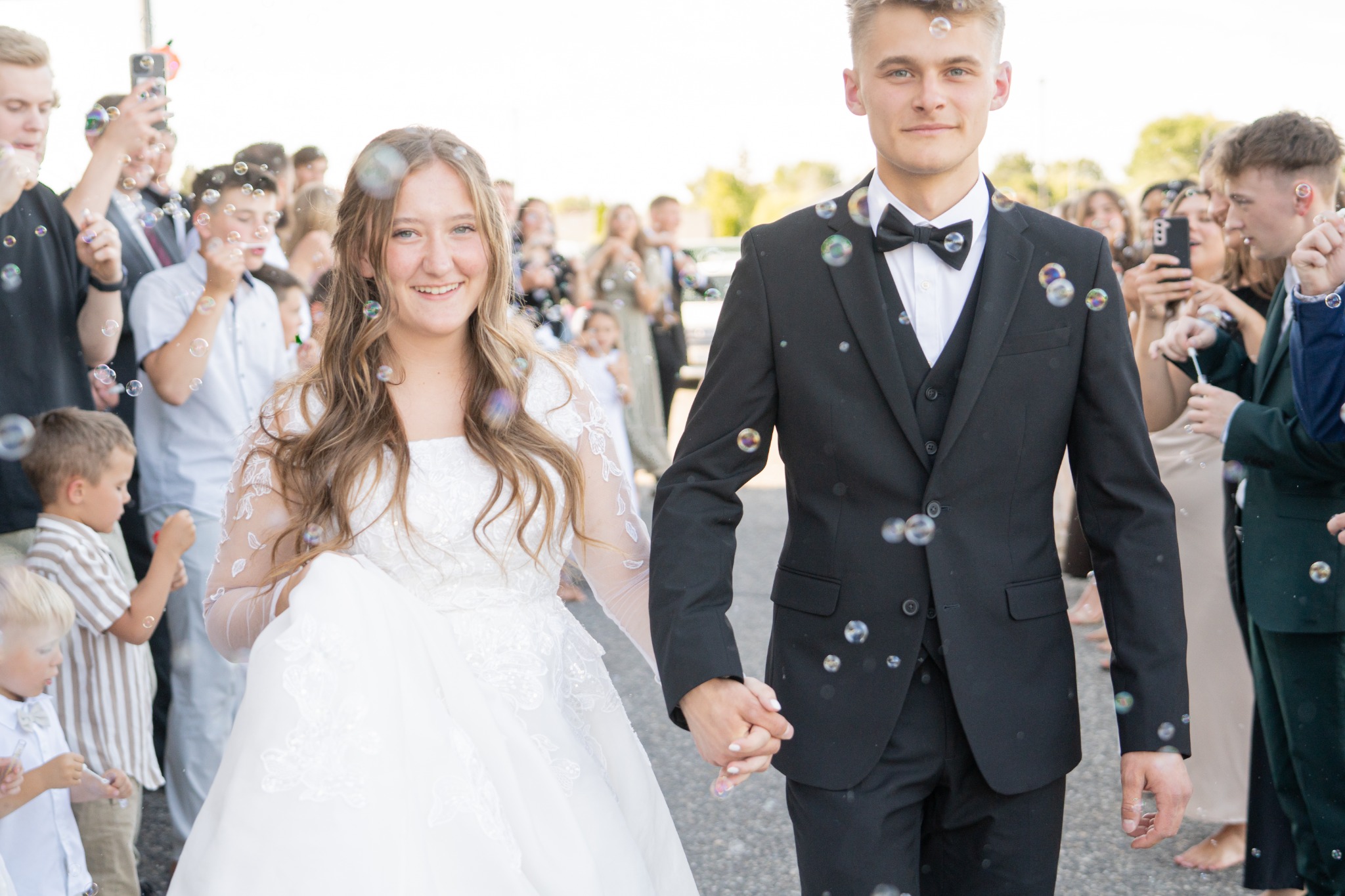 Newlyweds walking hand in hand through bubbles after their ceremony.