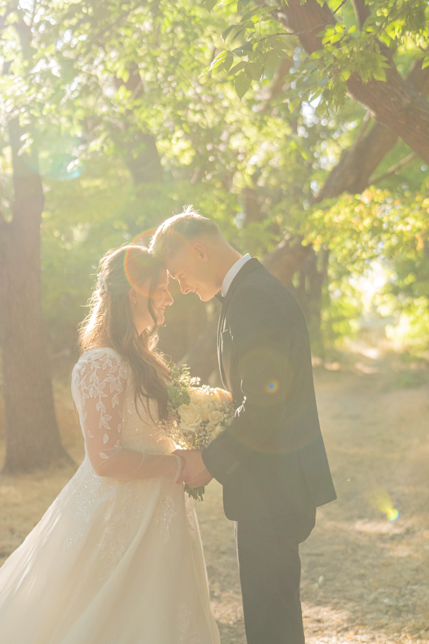 A bride and groom resting their foreheads together in warm golden light.