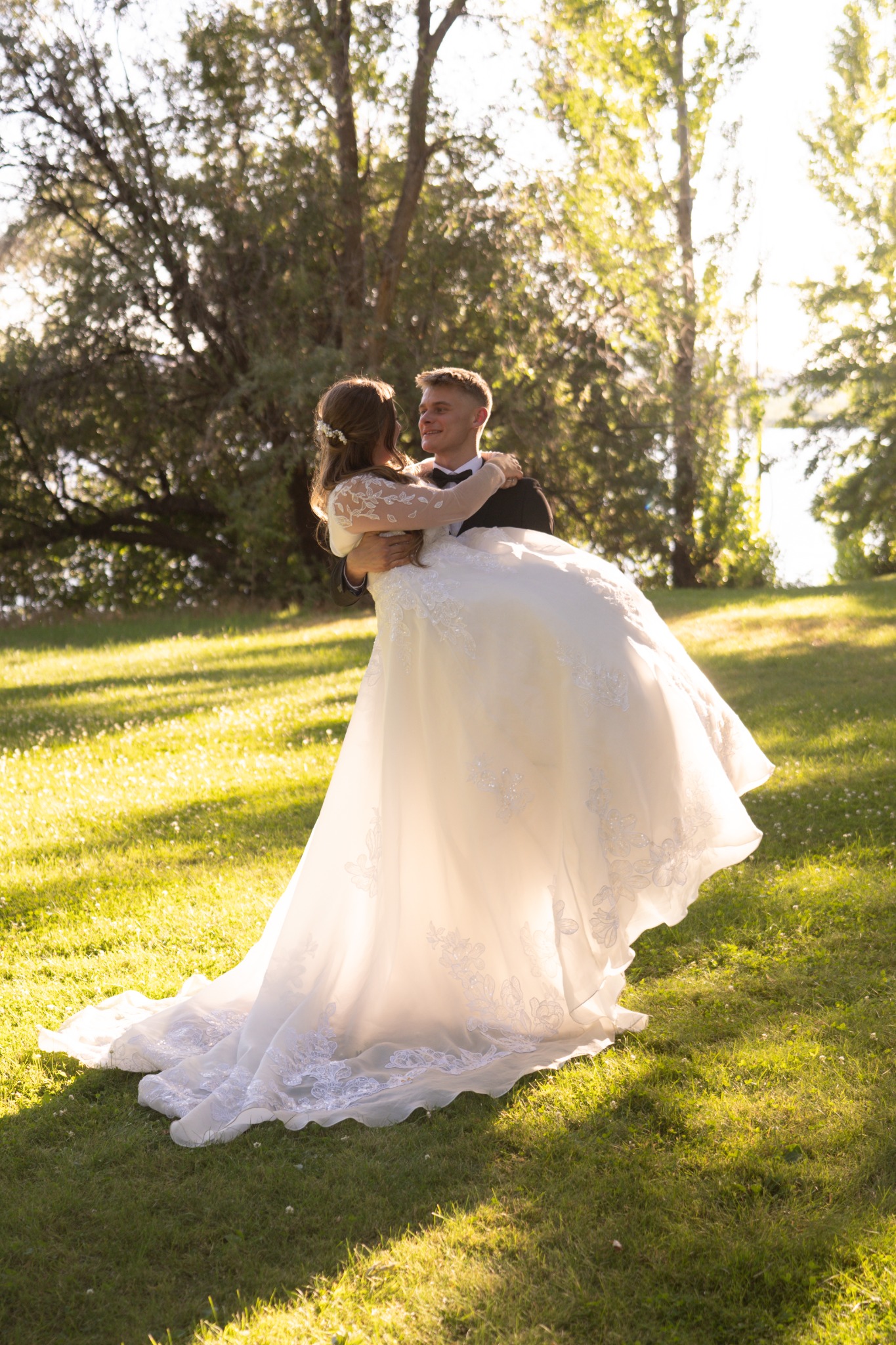 A groom lifting his bride in a sunlit garden after their ceremony.